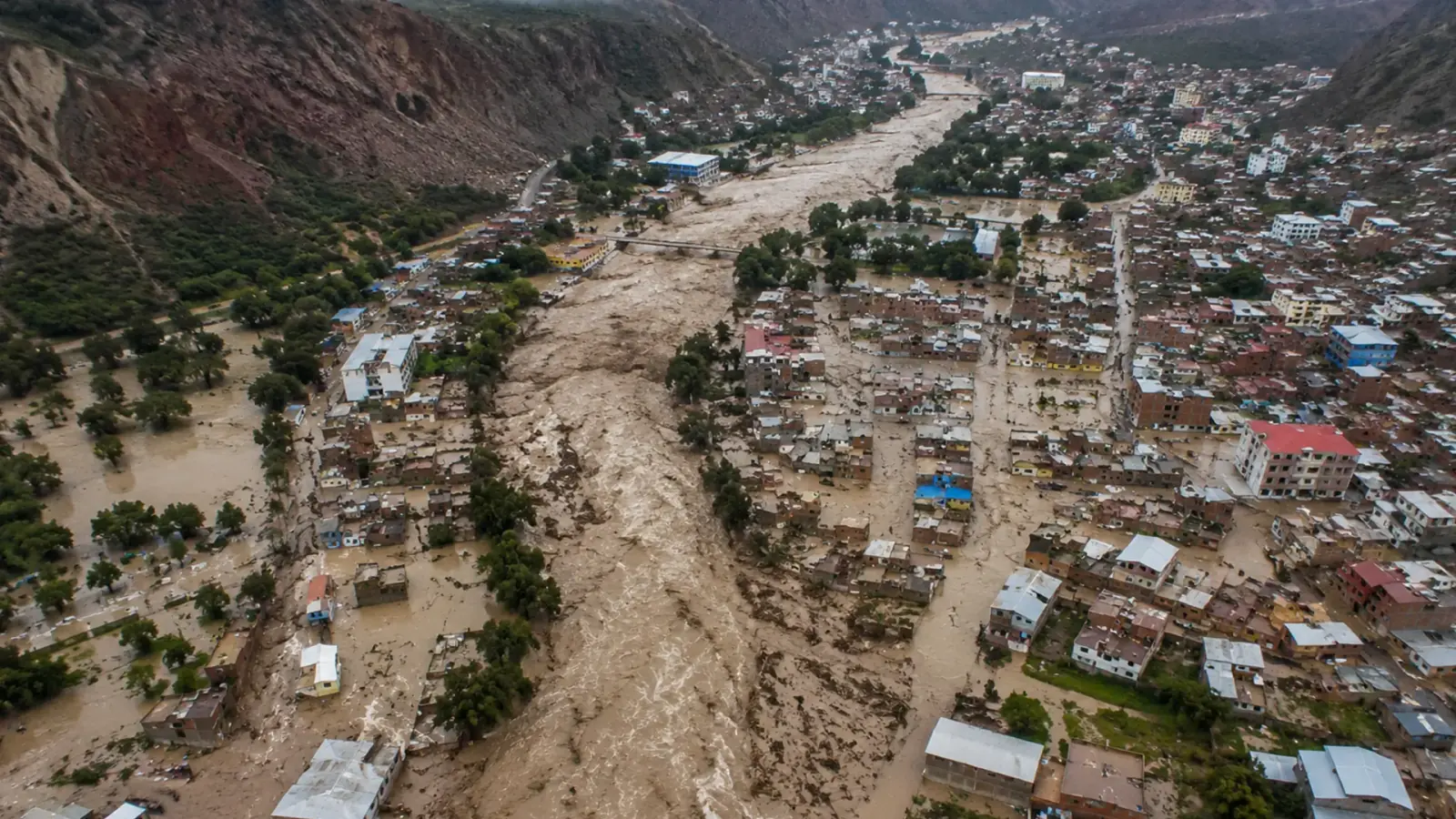 Vista aérea de un huaico atravesando un centro poblado en los Andes